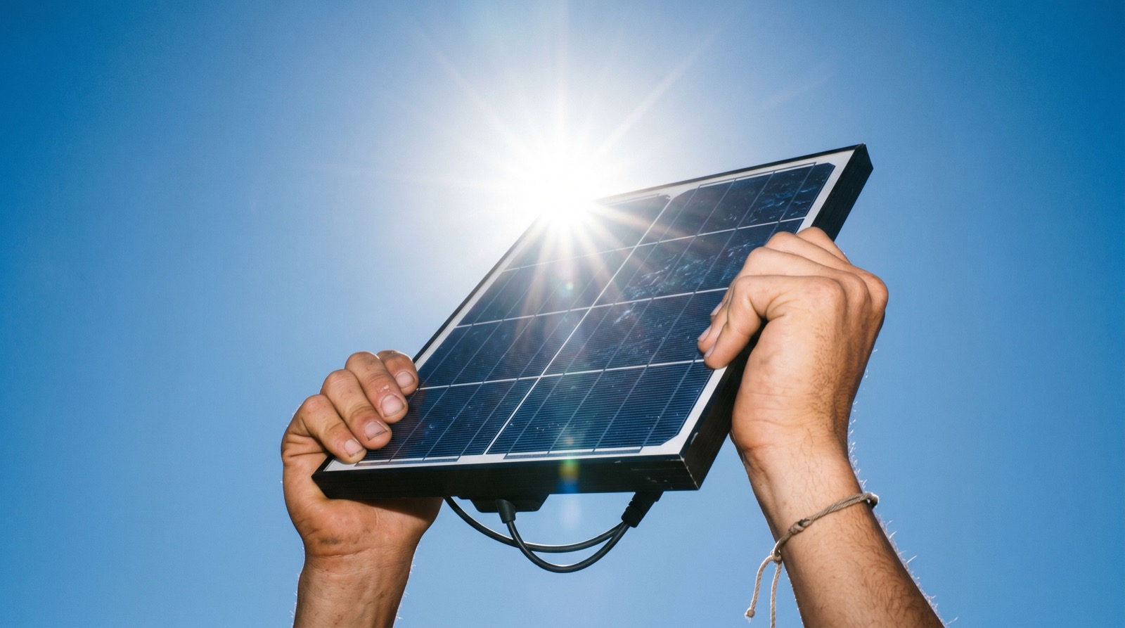 Hands holding a solar panel toward the sun